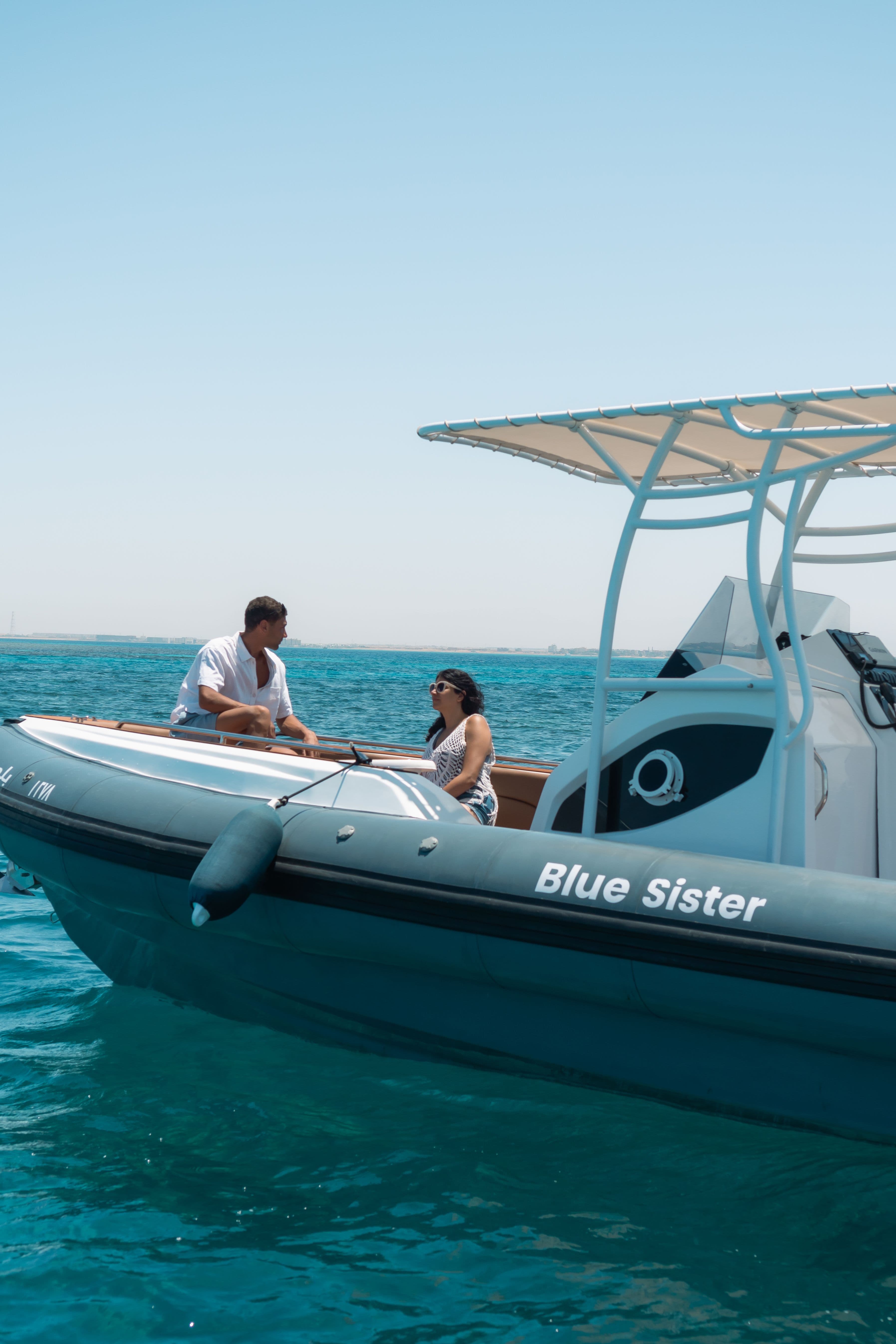 A man steering a small boat while a woman sits beside him, looking on.