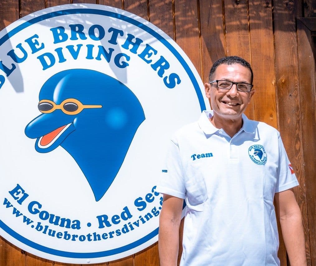 Kareem from the Blue Brothers Diving team beside the dive center sign