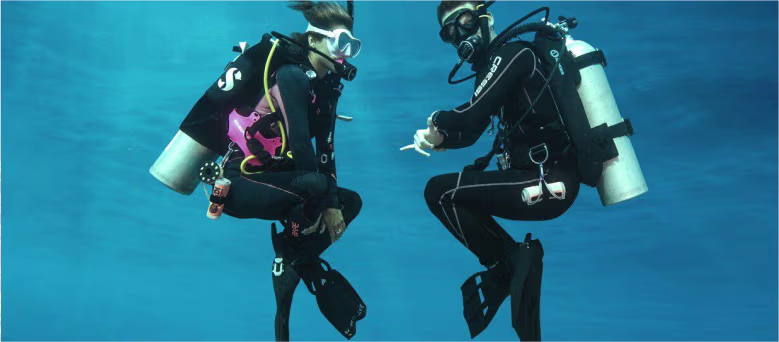 Two divers practicing buoyancy control underwater
