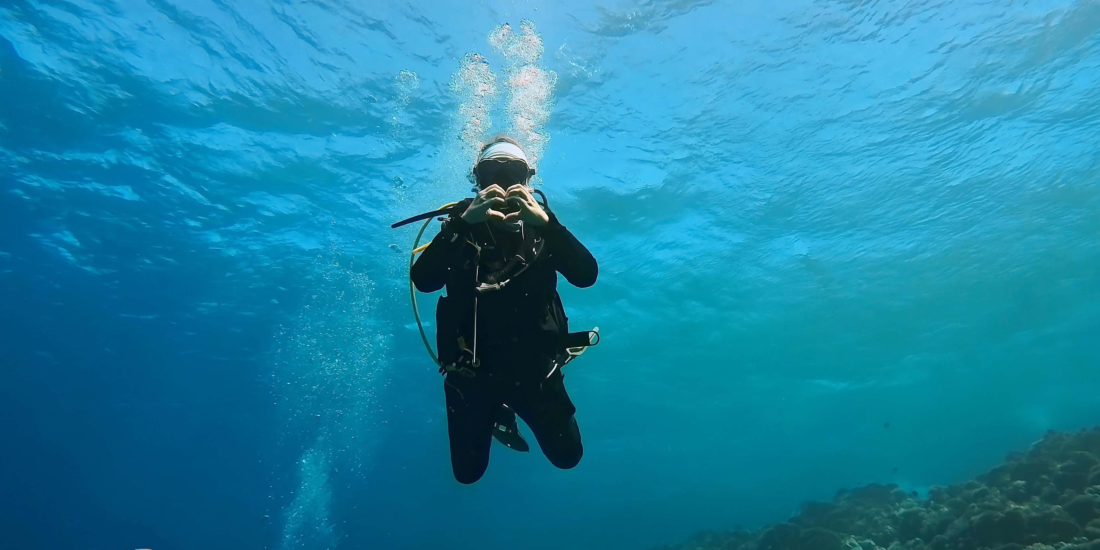 Diver showing a heart sign to express love for the underwater world
